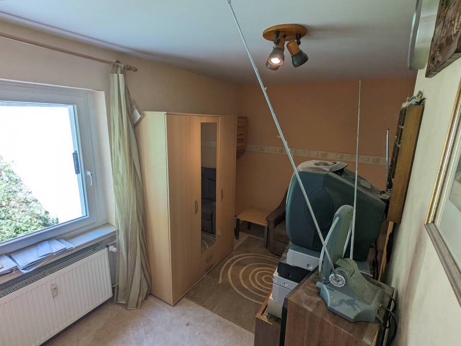 Entrümpelung in Binger nachher: ein aufgeräumter Raum ist mit einem Schrank und Röhrenfernseher zu sehen.